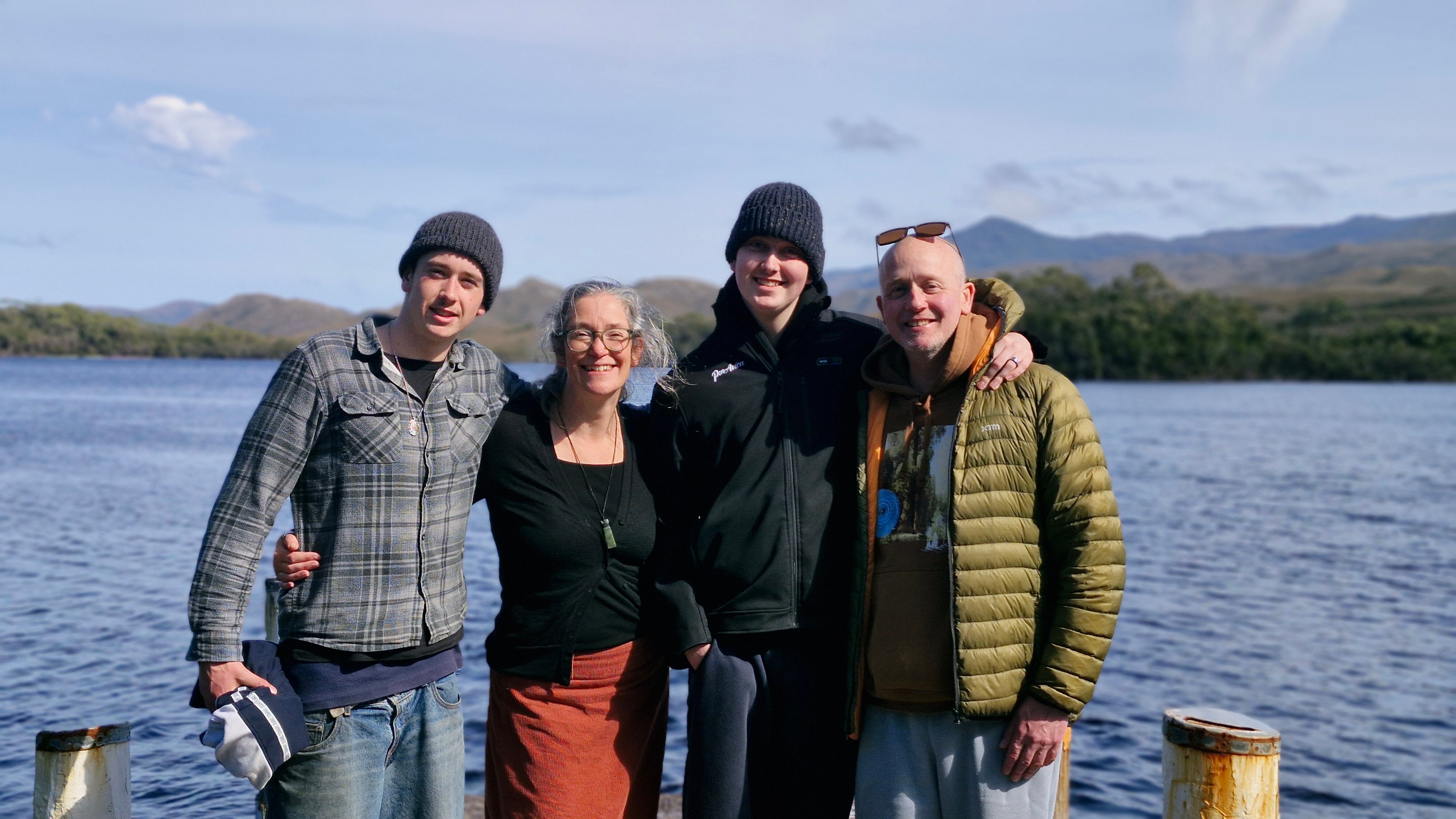 Two boys, a mum and a dad pose for a photo in front of the water.
