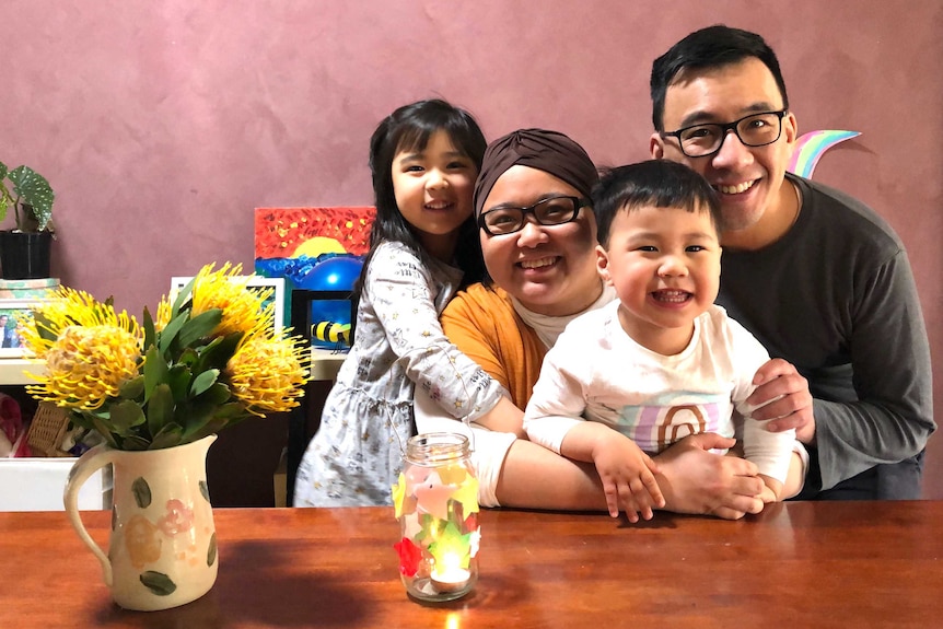 A family of four in front of a pink wall.