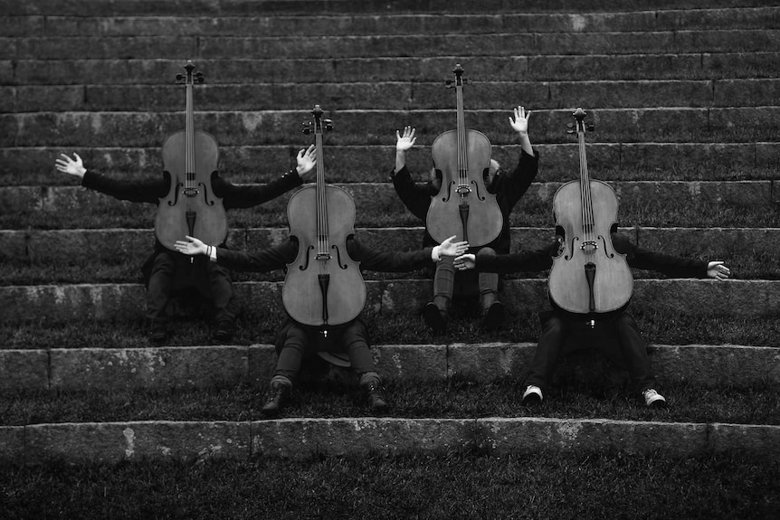 Musicians dressed as Cellos sitting on stairs.