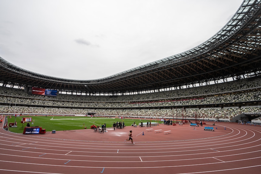 A test athletics event takes place in an empty stadium.