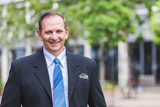 A smiling man in a dark suit.