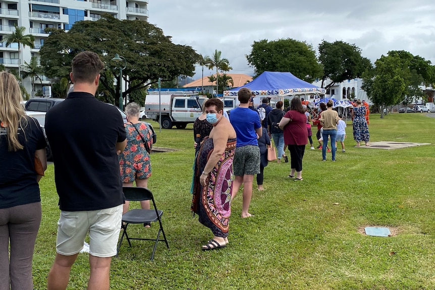 People lined up wearing masks while waiting to be tested along the Cairns esplanade. 