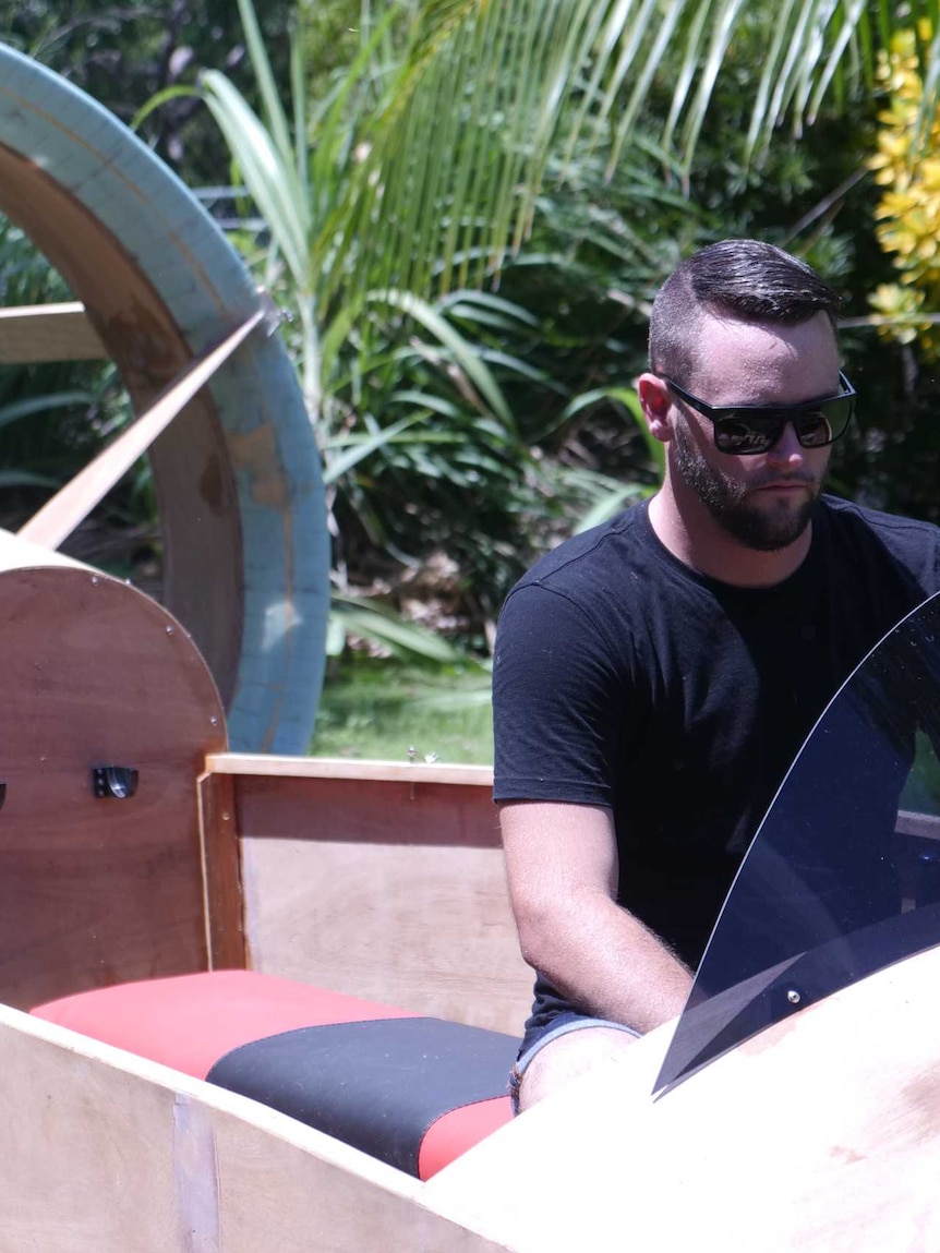 A man sits in a hovercraft in a yard.