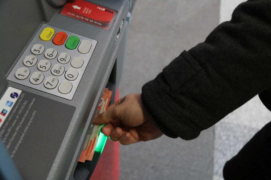 El hombre saca dinero en efectivo del cajero automático