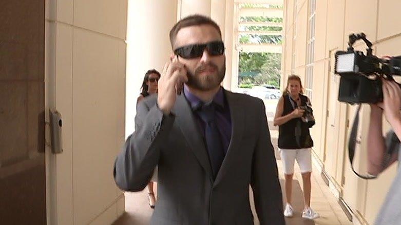 A man in a suit and tie speaking on a phone outside court.
