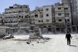 A rebel fight inspects a site damaged by Syrian air strikes