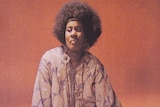Alice Coltrane looks away from the camera, against an orange background, from the cover of Journey in Satchidananda