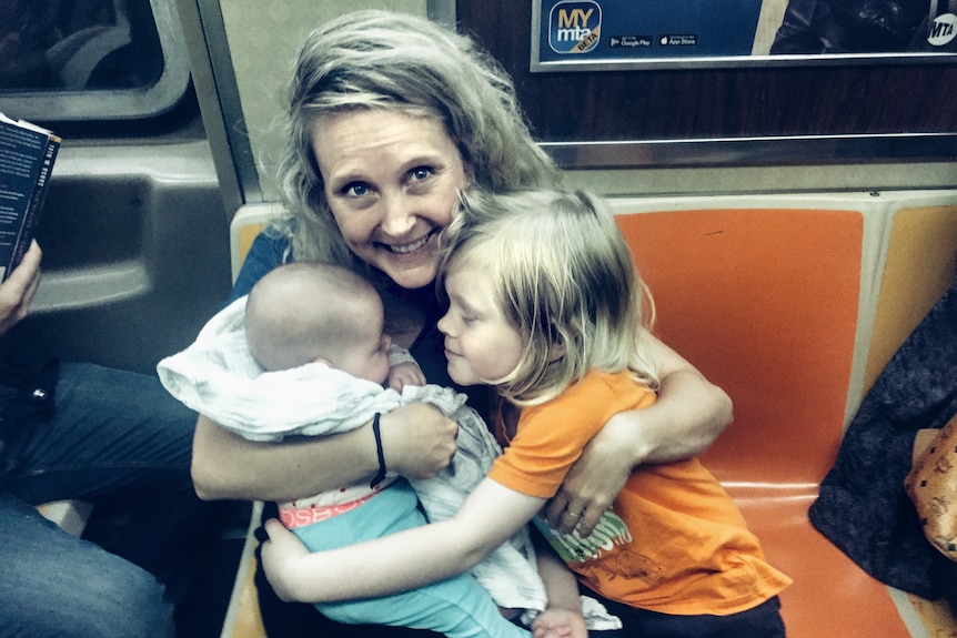 A woman hugging her two children on the subway