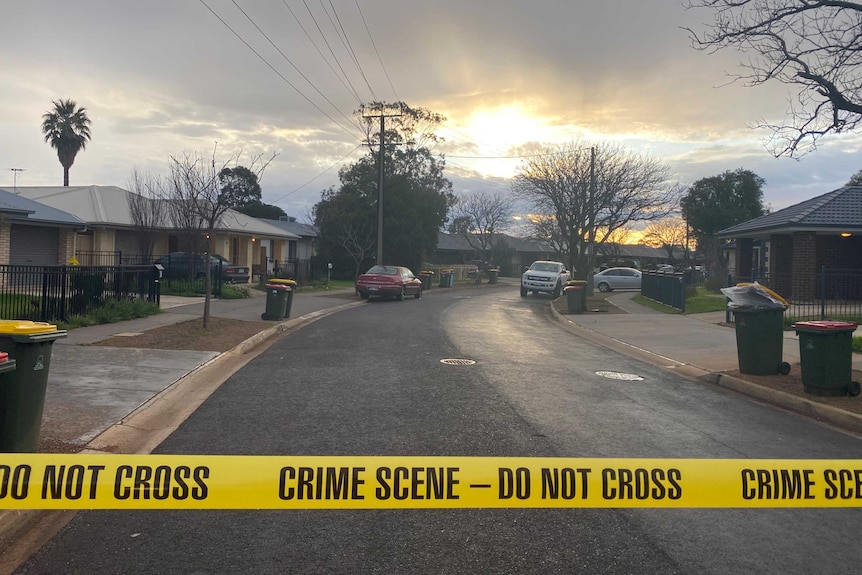 Crime scene tape divides a suburban street.