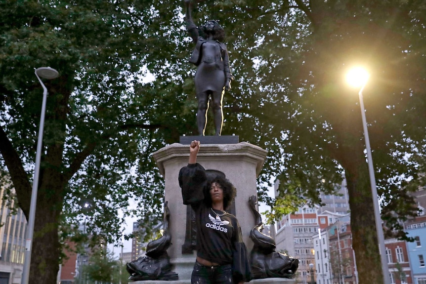 Jen Reid poses for photographs in front of the new black resin and steel statue.