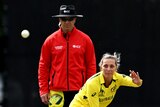 Ash Gardner bowls wearing yellow cricket kit