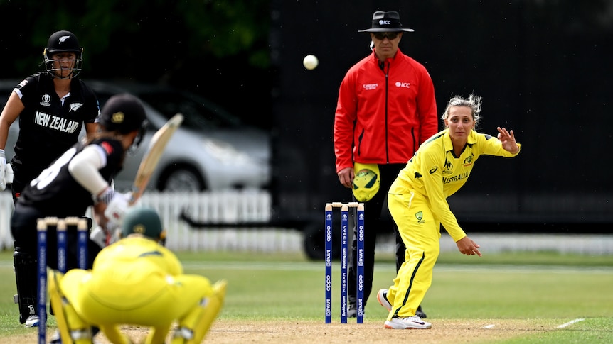 Ash Gardner bowls wearing yellow cricket kit