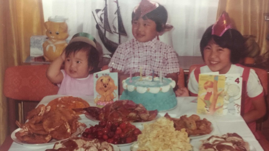 An archival photo of Hetty McKinnon in the eighties, at a family dining table surrounded by food and meat.