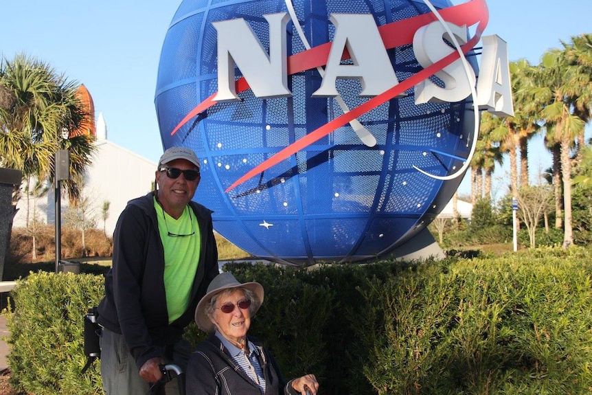 Norma and her son Tim in front of a NASA sign.