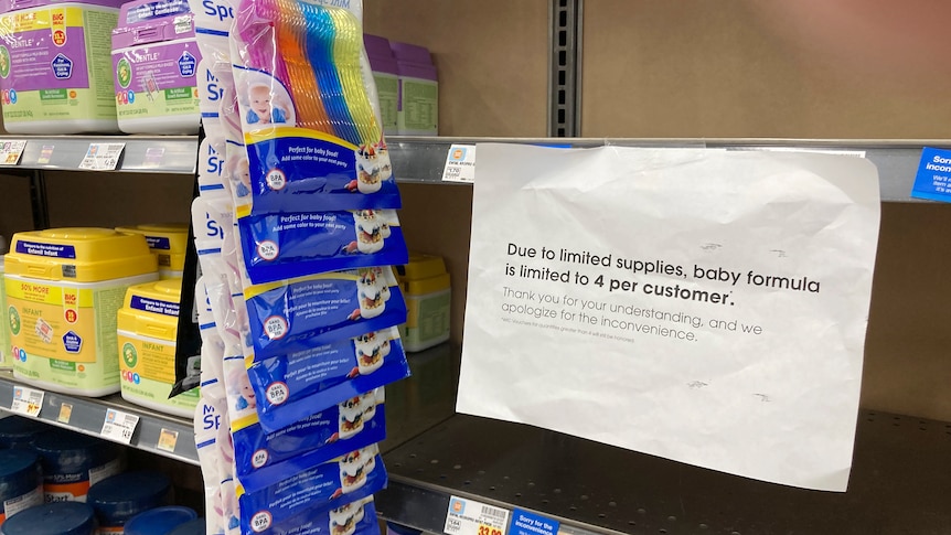 empty supermarket shelves with a sign reading "due to limited supplies, baby formula is limited to 4 per customer"