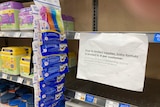 empty supermarket shelves with a sign reading "due to limited supplies, baby formula is limited to 4 per customer"