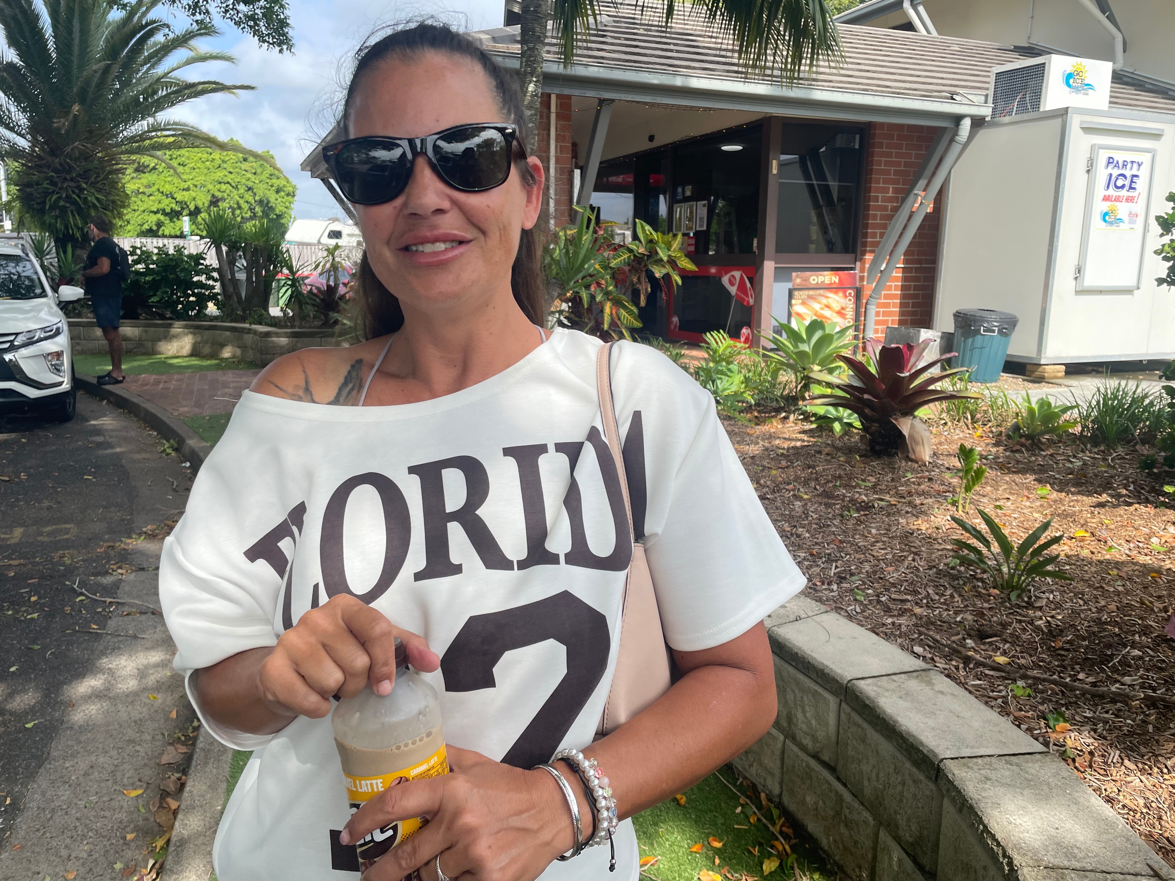 Mulher de óculos escuros e camiseta sorri.