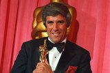 Man poses with Oscar award.