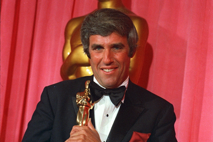 Man poses with Oscar award.
