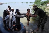 A man lifts a child to safety from a small boat carrying other people. 
