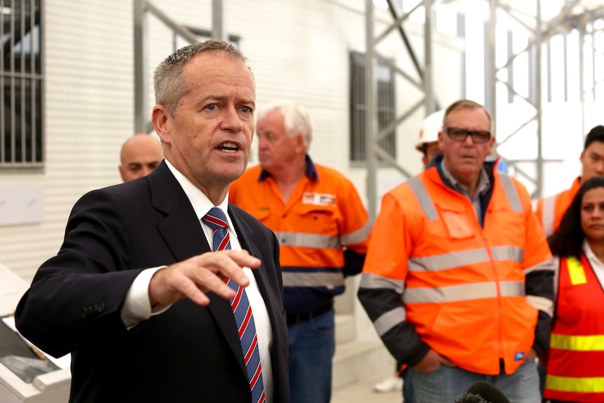 Bill Shorten points as he talks to a group of workers in high-vis
