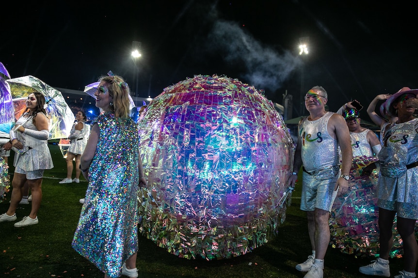 people wearing silver holding a big silver ball 