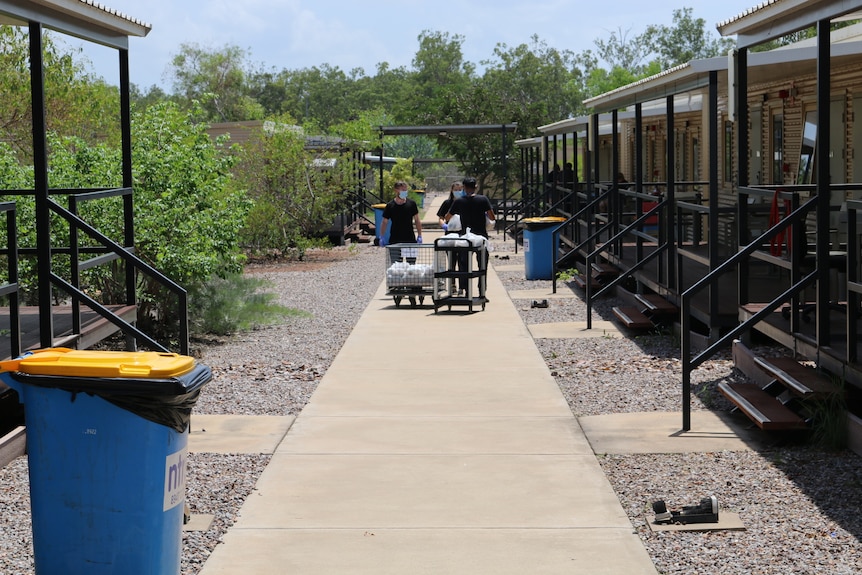 Two workers push a trolley between accommodation blocks at the Howard Springs quarantine facility.