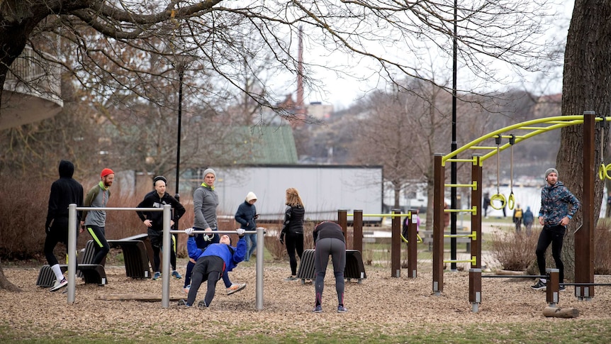 A group of people use outdoor gym equipment in a park in Sweden during the coronavirus pandemic