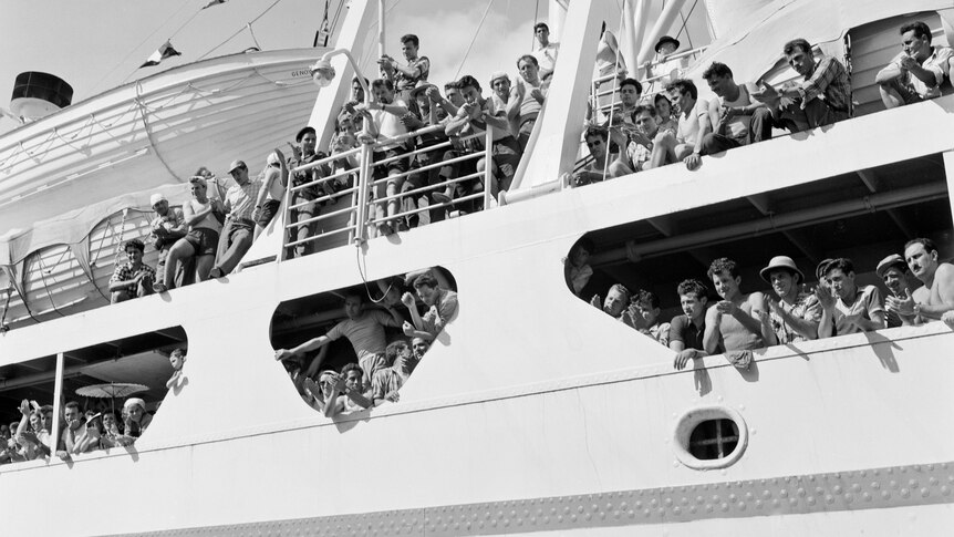 A 1950s black and white photo of a crowded ship arriving.