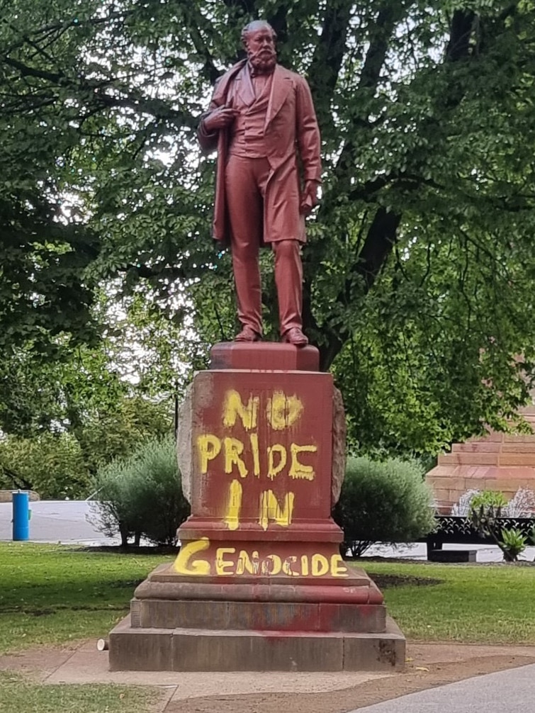 The words 'No pride in genocide' painted on a statue base.