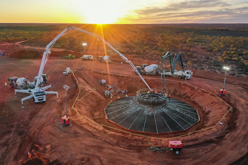 A remote mine site at sunset where concrete is being poured for the footings of a wind turbine.  