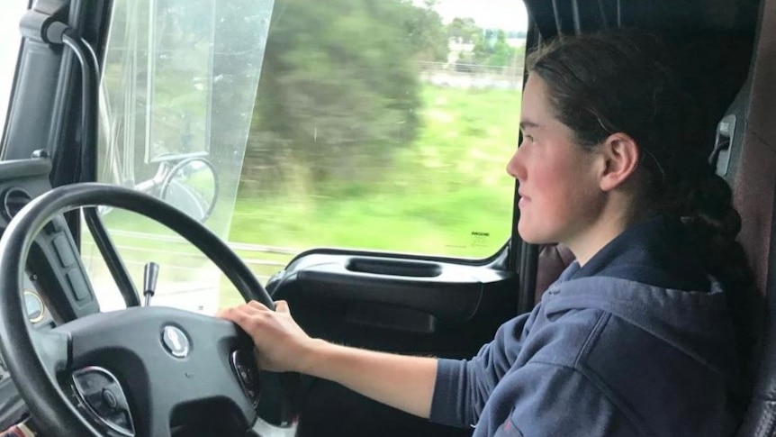 A women in her early 20s behind the steering wheel of a truck 