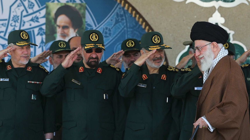 Iranian supreme leader walks past Revolutionary Guards who are in uniform and saluting him