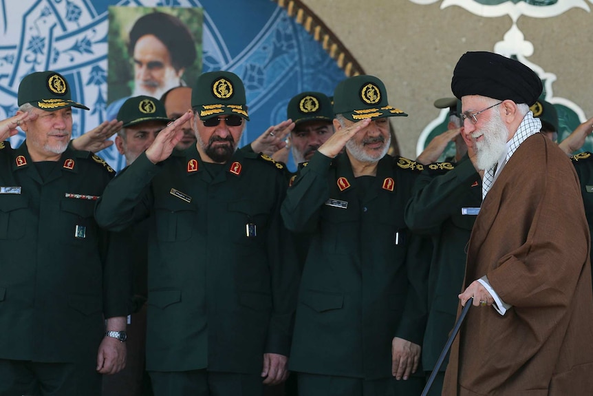 Iranian supreme leader walks past Revolutionary Guards who are in uniform and saluting him