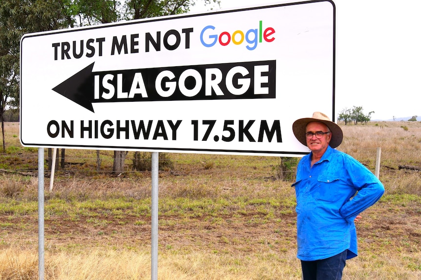 A farmer stands beside a sign that says, "Trust me not Google". 
