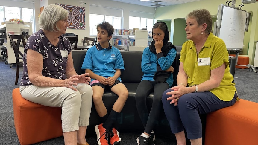 Two grandmothers sit with two students.