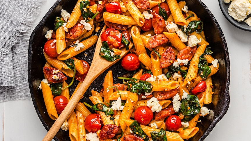Pan full of pasta sauce, made from chorizo, spinach and cherry tomatoes