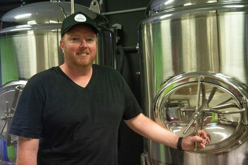 Pub-owner Kyle Pearson stands in smiles in his brewery.