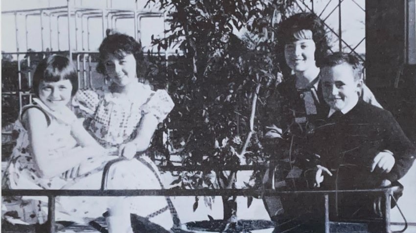 A black and white photo of a woman and three children. 