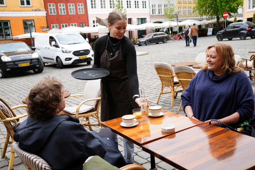 two women sit on opposite sides of a round cafe table.