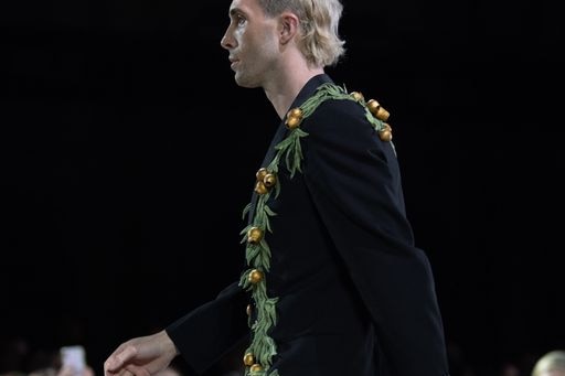 A man in a black suit with green leaves and gold adorning the leaves.