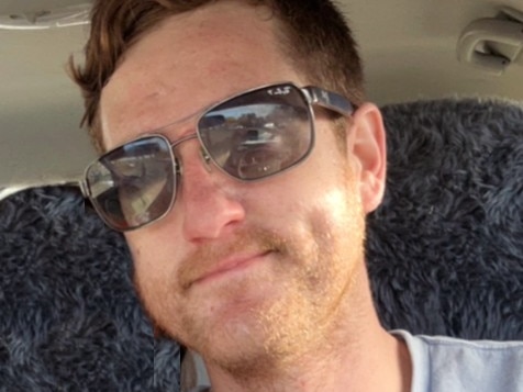 A young man with a stubbly beard who is wearing sunglasses.