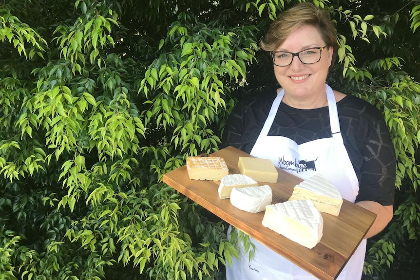 Woombye cheese company's Karen Paynter smiling and holding a platter of cheese.