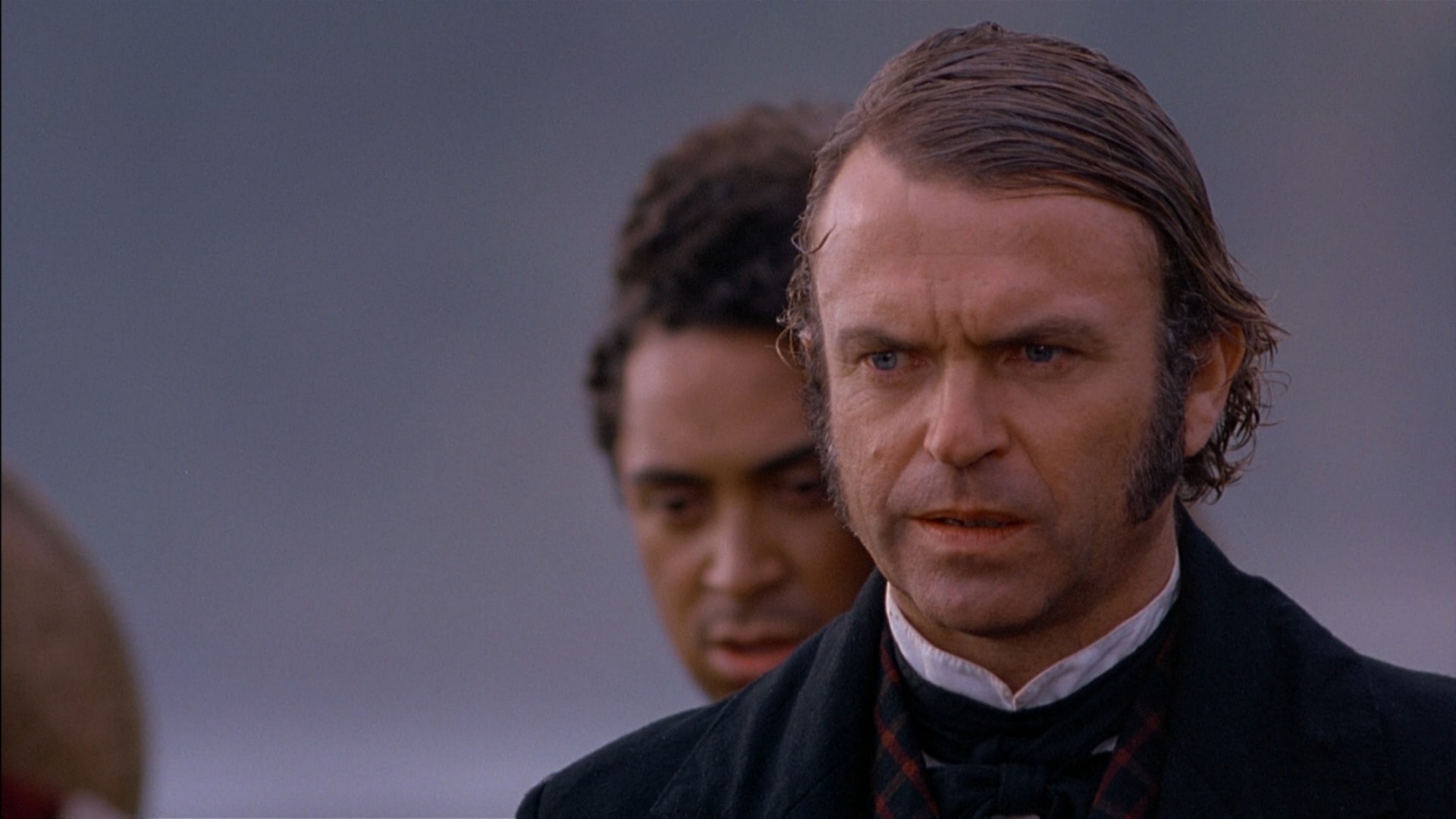 a windswept man on the beach in an old fashioned suit