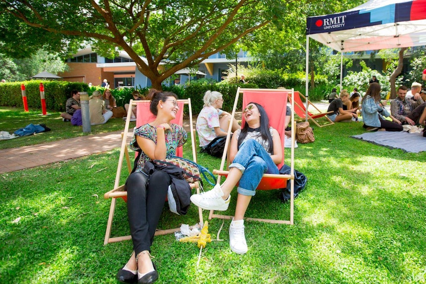 University students sit on beach chairs on the grass at RMIT's campus.