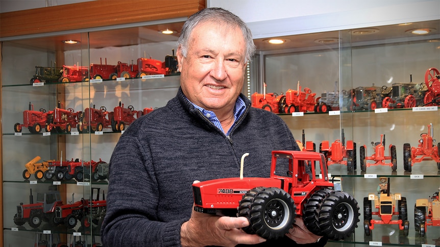 Phil Morris holds a model tractor in front of a glass case of tractors in Wellington.