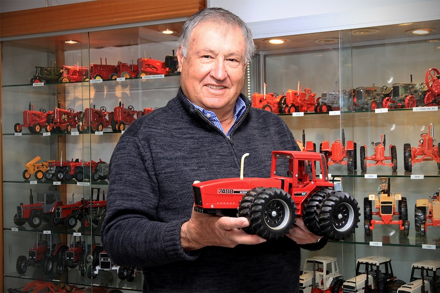 Phil Morris holds a model tractor in front of a glass case of tractors in Wellington.