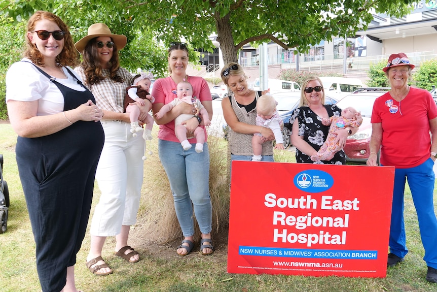 Women holding babies and a sign