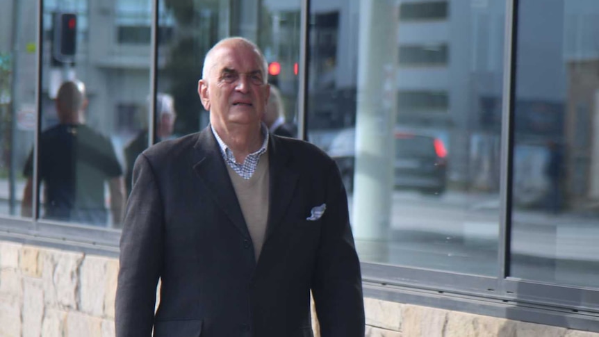 A man in a suit walks outside a building.