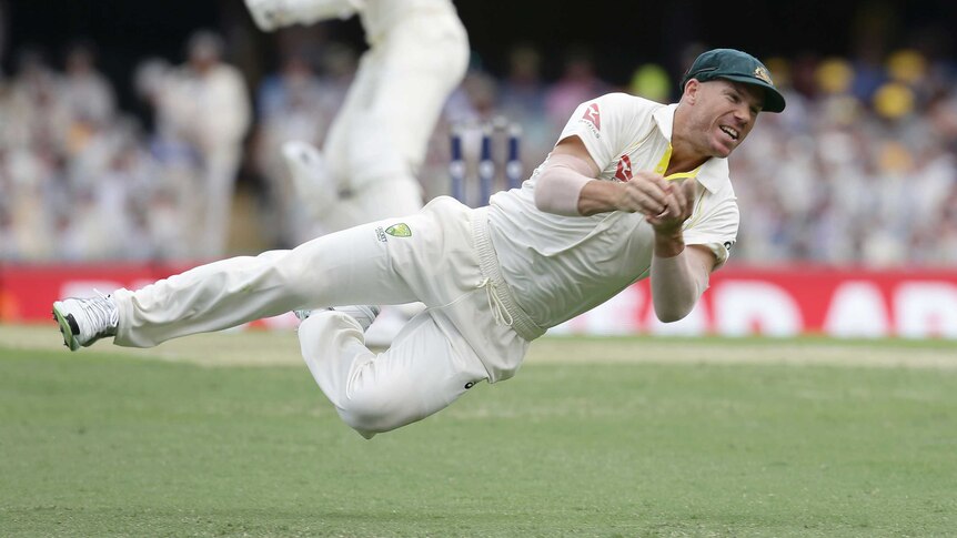 Australia's David Warner dives for a catch to dismiss England's Jake Ball on day two at the Gabba.